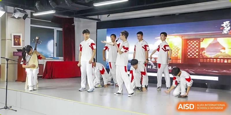 A group of male students from Xishan School of The High School Affiliated to Renmin University of China in matching white outfits on a stage, performing a routine.