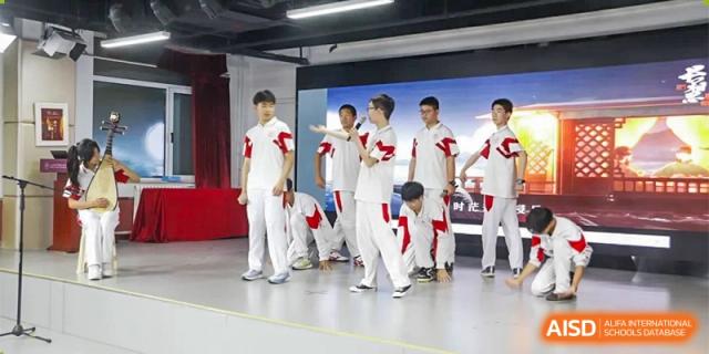 A group of male students from Xishan School of The High School Affiliated to Renmin University of China in matching white outfits on a stage, performing a routine.