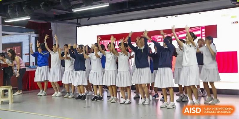 Students from Xishan School of The High School Affiliated to Renmin University of China cheer and raise their arms on a stage during a performance.