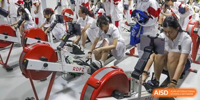 Xishan School of The High School Affiliated to Renmin University of China students exercising with rowing machines indoors.