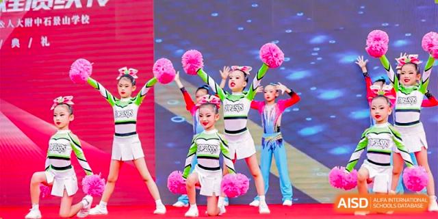 Young students from Xishan School of The High School Affiliated to Renmin University of China performing a cheer or dance on stage.