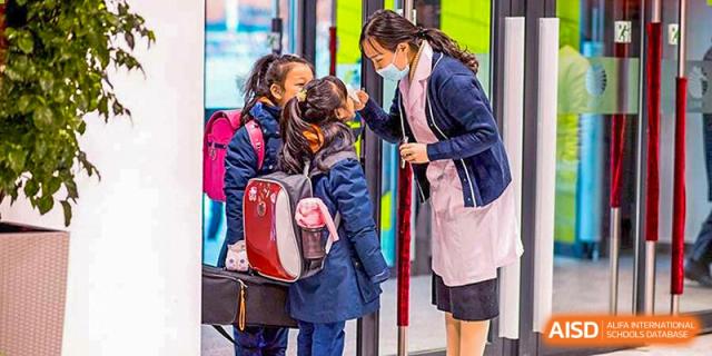 Students arrive at Yew Wah International Education School Of Beijing Yizhuang Campus, greeted by a teacher.