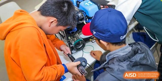 Male students at Yew Wah International Education School Of Beijing Yizhuang Campus work together on a robotics project.