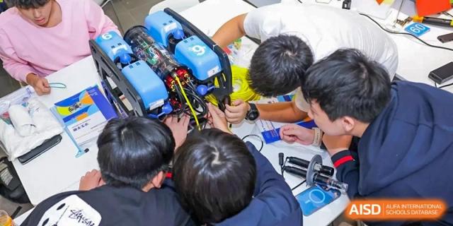 A group of male students at Yew Wah International Education School Of Beijing Yizhuang Campus works together on a robotics project.