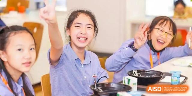 A happy student at Yew Wah International Education School Of Beijing Yizhuang Campus smiles and waves at the camera.