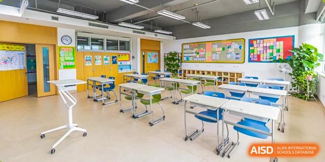 A wide shot of a modern, empty classroom with movable desks, chairs, and colorful wall displays at Yitian Hudson School.