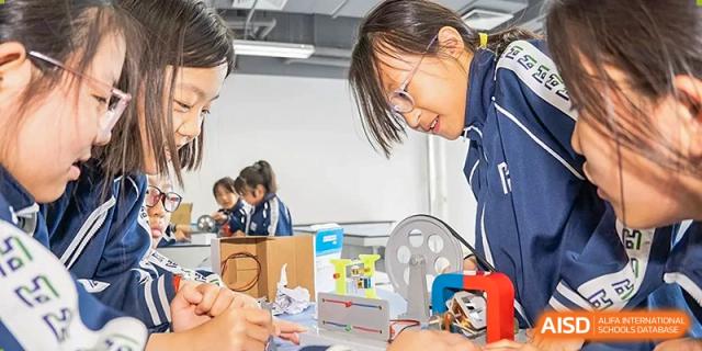 A female student concentrating on a hands-on science or engineering project involving paper and small devices at Yitian Hudson School.