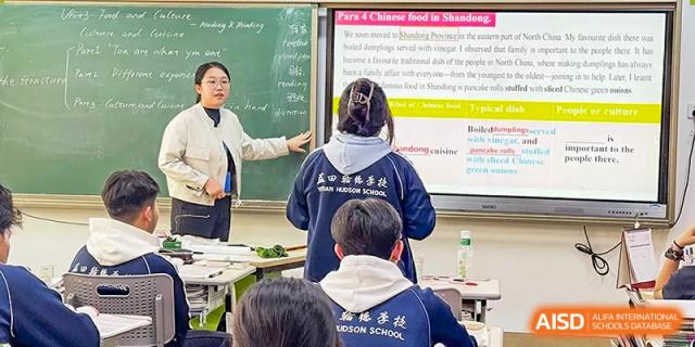 A student from the back, wearing a school backpack, participating in an active classroom discussion at Yitian Hudson School.