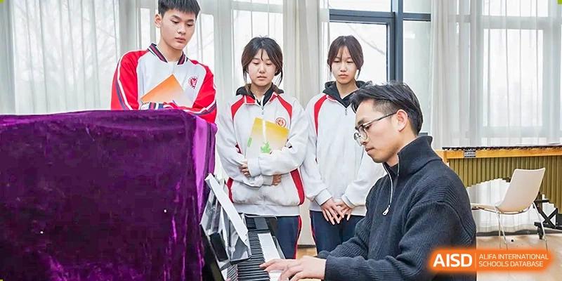 A group of students observing a teacher or instructor playing a piano during a music or performance class at Yitian Hudson School.
