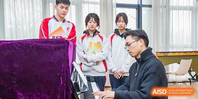 A group of students observing a teacher or instructor playing a piano during a music or performance class at Yitian Hudson School.