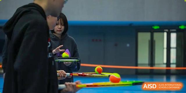 A student practicing with racquets and tennis or foam balls, focusing on hand-eye coordination at Yitian Hudson School.
