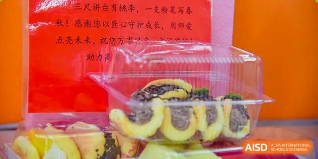 A close-up of a container of sliced fruit or pastries for a school snack, with Chinese characters on a red background at Yitian Hudson School.
