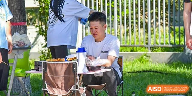 A student or staff member in a white shirt working on a clipboard outdoors, possibly involved in student services or health checks at Yitian Hudson School.