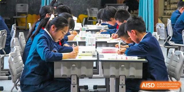 A close-up view of students at ZHANGQIU BILINGUAL INTERNATIONAL SCHOOL working diligently on written tests or assignments at their desks.