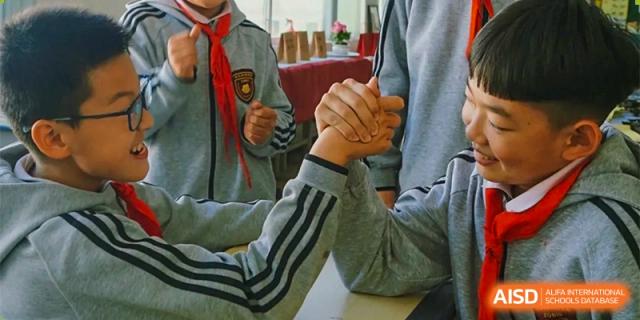 A close-up of two students at ZHANGQIU BILINGUAL INTERNATIONAL SCHOOL engaging in an arm-wrestling contest.