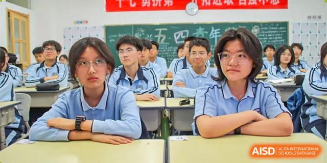 A group of male students at ZHANGQIU BILINGUAL INTERNATIONAL SCHOOL sit at their desks and listen to a class presentation.
