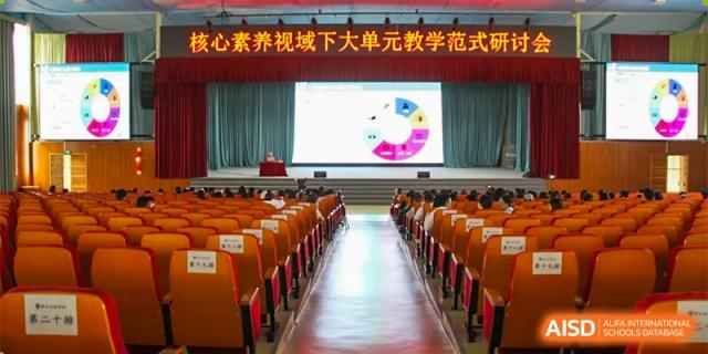 An auditorium or lecture hall at ZHANGQIU BILINGUAL INTERNATIONAL SCHOOL shows a large screen with a pie chart presentation on stage.