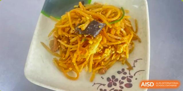A serving of savory stir-fried noodles with vegetables and slices of eggplant served at ZHANGQIU BILINGUAL INTERNATIONAL SCHOOL.