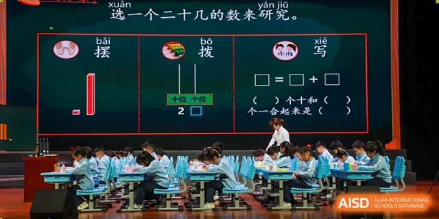 Students from Nanjing Dongshan Foreign Language School International Department are working on a math problem in a classroom with a whiteboard.