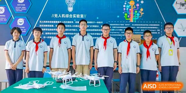 A group of students and a teacher from Nanjing Dongshan Foreign Language School International Department stand with a drone.