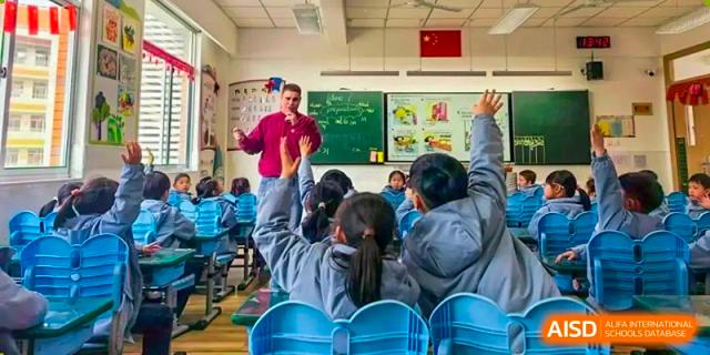 A teacher from Nanjing Dongshan Foreign Language School International Department is asking a question to students who are raising their hands.