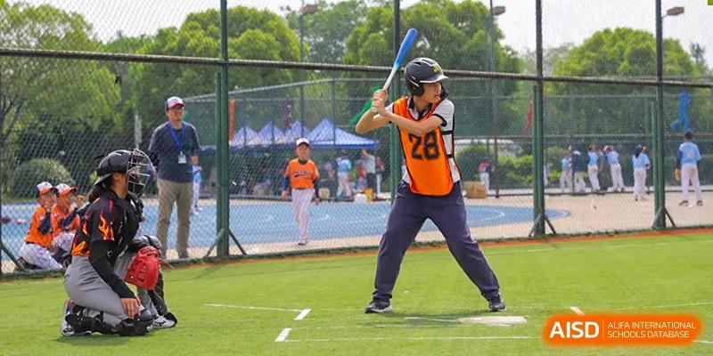 A person in an orange jersey from Nanjing Dongshan Foreign Language School International Department is stretching on a sports court.
