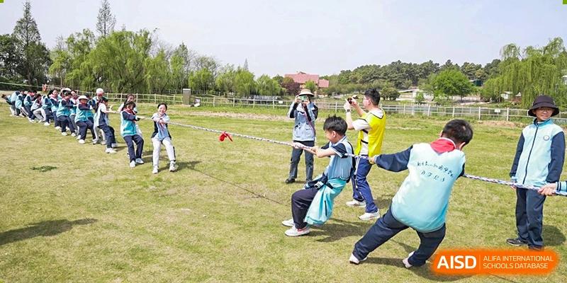 A group of students from Nanjing Dongshan Foreign Language School International Department walking on a grassy field with a teacher.