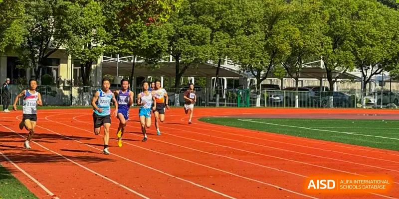A group of runners from Nanjing Dongshan Foreign Language School International Department are on a red track during a race.