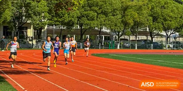 A group of runners from Nanjing Dongshan Foreign Language School International Department are on a red track during a race.