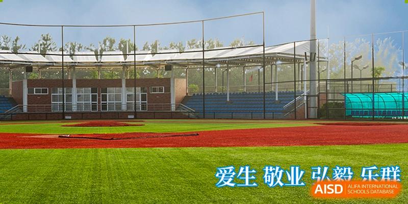 A green sports field with a running track, with the phrase "爱生敬" visible in the corner, at Nanjing Dongshan Foreign Language School International Department.