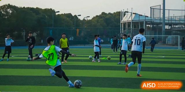 Students from Nanjing Dongshan Foreign Language School International Department are playing soccer on a green field.