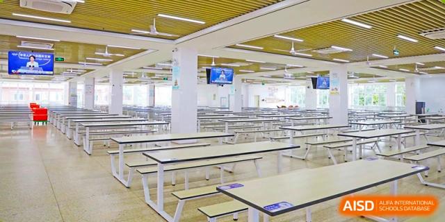 A large, empty cafeteria with rows of tables and benches at Nanjing Dongshan Foreign Language School International Department.