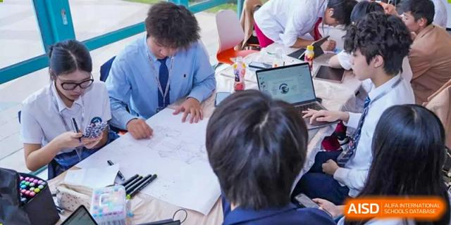 Students from Nanning No.2 High School International Division are working on a group project, sketching and collaborating at a desk.