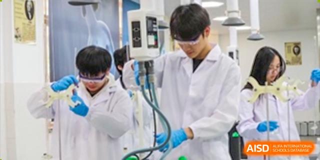 A close-up view of a student from Nanning No.2 High School International Division conducting a lab experiment, wearing a lab coat and gloves.