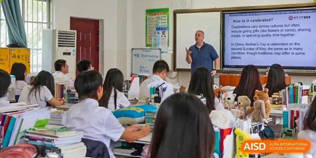 A teacher is giving a presentation to students from Nanning No.2 High School International Division in a classroom.