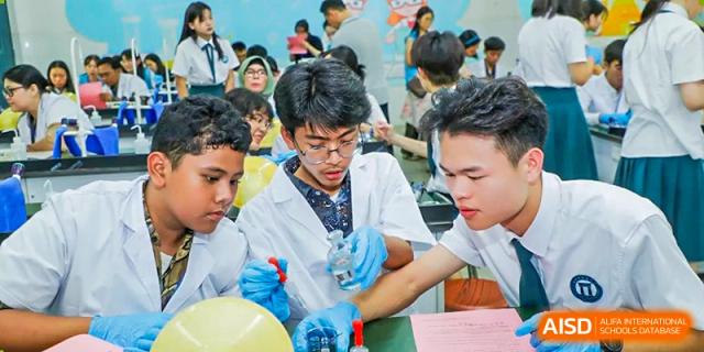 A student from Nanning No.2 High School International Division is focused on a science experiment, wearing a lab coat and safety glasses.