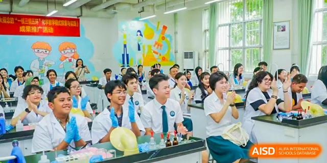 A group of students from Nanning No.2 High School International Division is smiling and looking at a science experiment with yellow balloons.