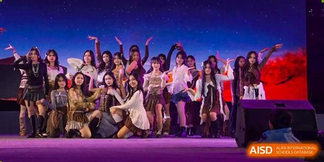 A group of students from Nanning No.2 High School International Division performing a dance routine on a stage with a starry background.