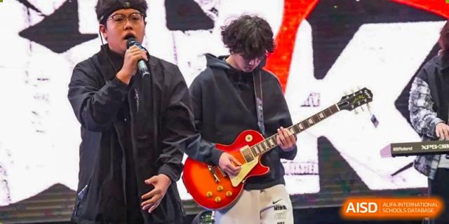 A student from Nanning No.2 High School International Division playing a red electric guitar on stage in front of a crowd.