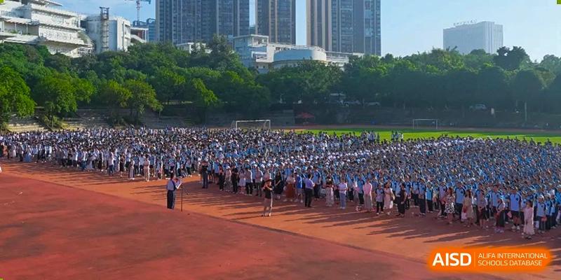 An aerial view of a large group of students from Nanning No.2 High School International Division gathered on a sports field for an event.