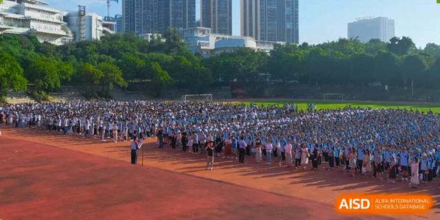 An aerial view of a large group of students from Nanning No.2 High School International Division gathered on a sports field for an event.