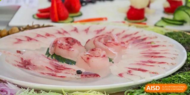 Slices of raw fish are prepared on a plate, possibly from the cafeteria or a school event at Nanning No.2 High School International Division.
