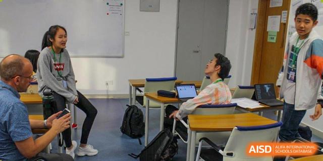 A student from BASIS International & Bilingual Schools Chengdu sitting at a desk with a laptop, looking out a window.