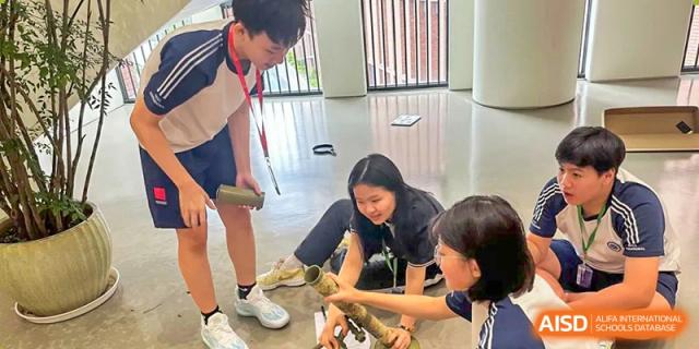 Students from BASIS International & Bilingual Schools Chengdu on the floor, working on a project with small devices.