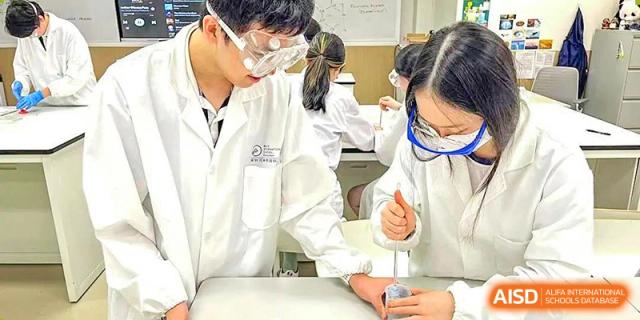 A BASIS International & Bilingual Schools Chengdu student wearing a lab coat and safety goggles, working on a science experiment.