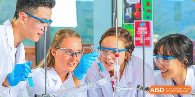 Students and a teacher from BASIS International & Bilingual Schools Chengdu smiling while working together on a science experiment.