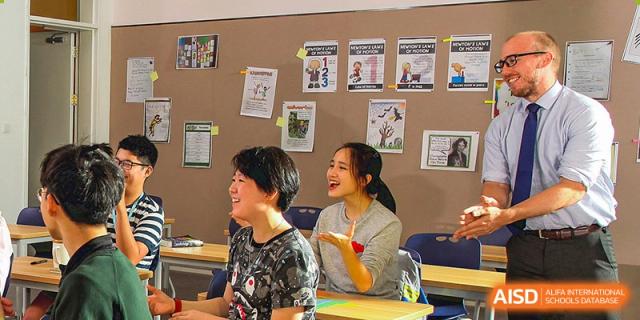 Students and a teacher from BASIS International & Bilingual Schools Chengdu in a classroom, talking and laughing together.