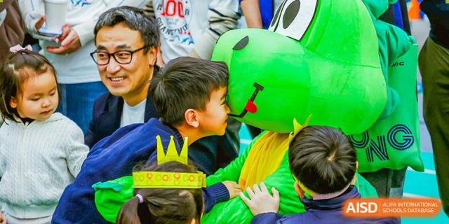 A young student from BASIS International & Bilingual Schools Chengdu hugging a person in a green mascot costume.