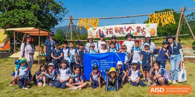 A group of students and teachers from BASIS International & Bilingual Schools Chengdu holding a blue banner during a school trip or event.