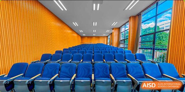An empty auditorium with rows of blue chairs at BASIS International & Bilingual Schools Chengdu.